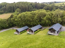 A view of three houses situated on grass near trees at Barcud Coch - Red Kite in Garthmyl