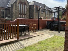 A garden with a table and chairs near a hot tub at The Furness Haven in Barrow-In-Furness