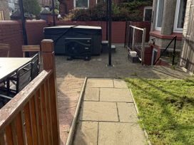 A garden with a table, chairs, and a hot tub at The Furness Haven in Barrow-In-Furness