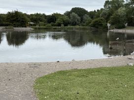 A lake surrounded by grass and trees with birds at The Furness Haven in Barrow-In-Furness