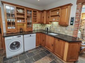 A kitchen with cabinets, washing machine, and dishwasher at Rose House in Alnmouth