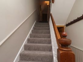A staircase with a handrail and light fixture at Rose House in Alnmouth
