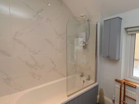 A bathroom featuring a bathtub with a shower and a wall cabinet at Rose House Alnmouth