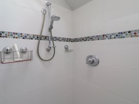 A shower with decorative tiles and shower fixtures at Rose House Alnmouth
