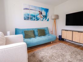 A living room with a sofa and wall art at Lavender House in Crantock