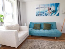 A living room with a sofa, armchair, and a painting at Lavender House, Crantock