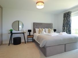 A bedroom featuring a bed, bedside tables, and a mirror at Lavender House in Crantock