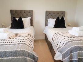 A bedroom with twin beds and towels at Lavender House in Crantock