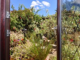 A view of a garden from an open door at Turnpike Lodge in Brixham