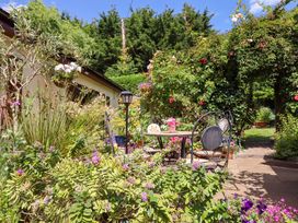 A garden with a table and chairs surrounded by flowers at Turnpike Lodge in Brixham