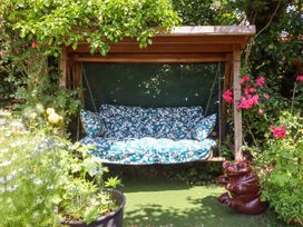 A swing with cushions surrounded by flowers and a decorative statue at Turnpike Lodge in Brixham