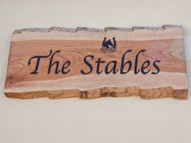 A wooden sign that reads The Stables at The Stables at Hall Barn in Wattisfield near Walsham-Le-Willows