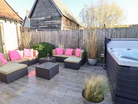 An outdoor patio with a hot tub and seating area at The Stables at Hall Barn in Wattisfield near Walsham-Le-Willows