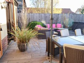 An outdoor area with a table, chairs, and a sofa at The Stables at Hall Barn Wattisfield near Walsham-Le-Willows