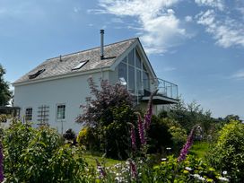 A house with a balcony surrounded by a garden at Spires Playing Place near Carnon Downs