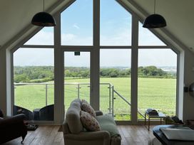 A living room with large windows overlooking a field at Spires in Playing Place near Carnon Downs