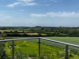 A balcony view overlooking fields and hills at Spires Playing Place near Carnon Downs