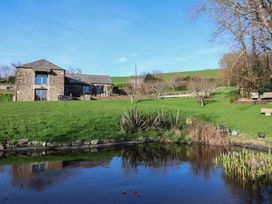 A house with a pond and grass in the background at Birchenhayes St Dominick
