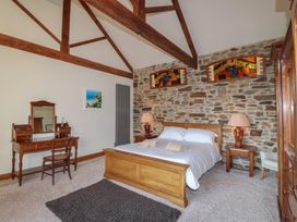 A bedroom with a bed and a wooden wardrobe at Birchenhayes in St Dominick