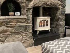A living room with a fireplace and stone wall at Old Chapel House in Llanfairfechan