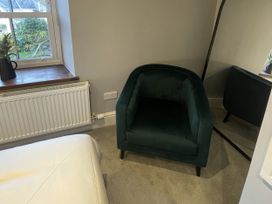 A bedroom with an armchair and a window at Old Chapel House in Llanfairfechan