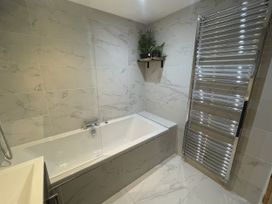 A bathroom with a bathtub and towel radiator at Old Chapel House in Llanfairfechan