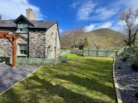 A garden with a stone house and mountain in the background at Old Chapel House Abergwyngregyn near Llanfairfechan