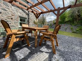 A garden with wooden furniture under a pergola at Old Chapel House Abergwyngregyn near Llanfairfechan