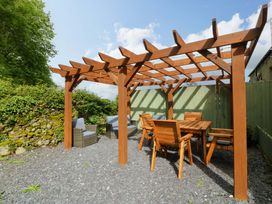 A garden with a pergola, dining table, and chairs at Old Chapel House in Abergwyngregyn near Llanfairfechan