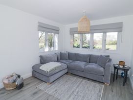 A sitting room with a grey corner sofa and windows showing a garden at New House Farm in Wappenbury near Leamington Spa
