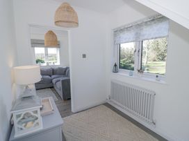A hallway with a window and radiator and a view into a room with a sofa at New House Farm in Wappenbury near Leamington Spa