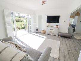 A living room with a gray sofa white rug and wall-mounted tv at New House Farm in Wappenbury near Leamington Spa