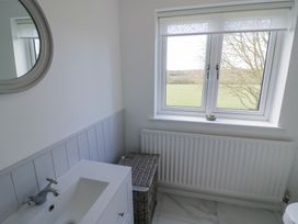 A bathroom with a sink and faucet a wicker basket under a window and a radiator at New House Farm in Wappenbury near Leamington Spa