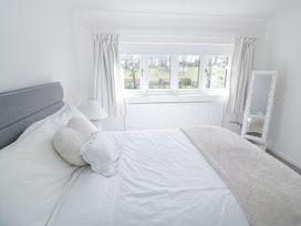 A bedroom with a bed with white and gray bedding a window with curtains a standing mirror and a lamp at New House Farm in Wappenbury near Leamington Spa
