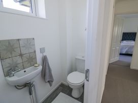 A small bathroom with a toilet and sink with tiles behind it and a towel hanging at New House Farm in Wappenbury near Leamington Spa