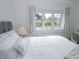 A bedroom with a bed lamp and window showing a view of a field at New House Farm in Wappenbury near Leamington Spa