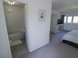 A bedroom with a bed television and a door leading to a bathroom at New House Farm in Wappenbury near Leamington Spa