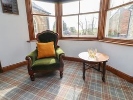 A snug with an armchair and side table at The Coach House in Crookham near Cornhill-On-Tweed