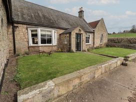 A garden with a stone wall and lawn at The Coach House in Crookham near Cornhill-On-Tweed