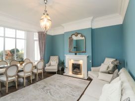 A living room with a fireplace a mirror armchairs a sofa and a dining table with chairs at Russell House in Paignton
