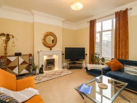 A living room with a fireplace a television orange and blue sofas and a glass coffee table at Russell House in Paignton