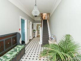 A hallway with a staircase a bench with a patterned cushion a plant and tiled floor at Russell House in Paignton