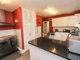A kitchen with white cabinets black countertops a stove and a refrigerator at Russell House in Paignton