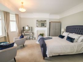 A bedroom with a bed pillows armchairs a vanity table a wardrobe and a fireplace at Russell House in Paignton