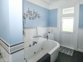 A bathroom with a white bathtub a sailboat model on the edge blue walls and a white door at Russell House in Paignton