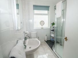 A bathroom with a sink toilet shower and shelving unit at Russell House in Paignton