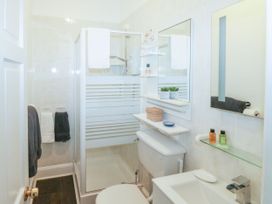 A bathroom with a shower enclosure toilet sink towels and mirrors at Russell House in Paignton
