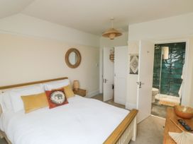 A bedroom with a bed white bedding pillows a wooden nightstand mirror and an open door showing a bathroom with green tiles at Russell House in Paignton