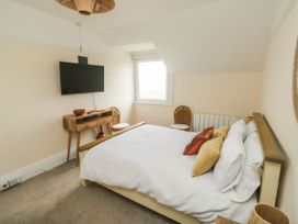 A bedroom with a bed with pillows a wall-mounted tv two chairs and a wooden desk at Russell House in Paignton