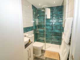 A bathroom with a toilet sink and a shower enclosure with green tiled walls at Russell House in Paignton